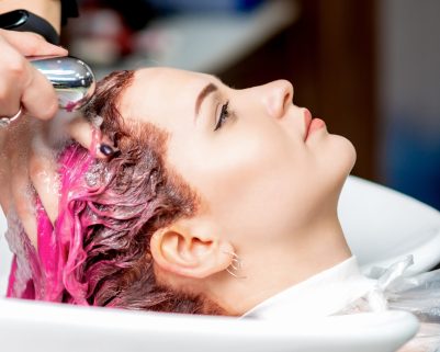 Close up of young woman having her colored hair washed in a beauty salon.