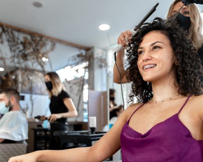 Low angle view photo of a hairdresser working on the hair of a woman sitting in front of a mirror