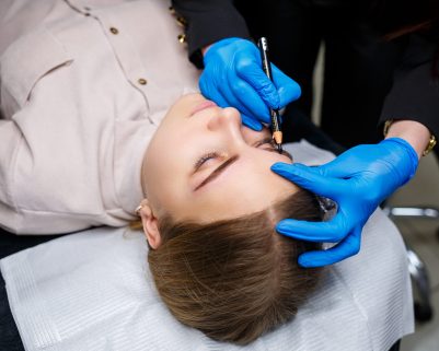 A make-up artist applies a sketch to the eyebrows of a young girl with an eyebrow pencil. Professional make-up and cosmetic skin care.